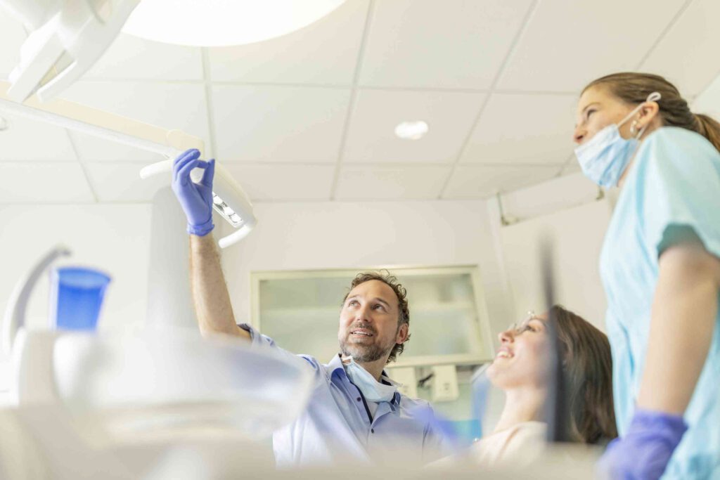 Zahnarzt Stegherr während der endodontologischen Behandlung mit einer Patientin und Assistentin.