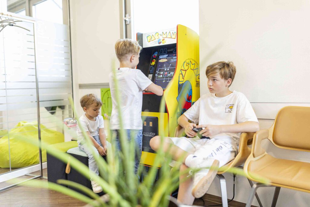 Kinder im Wartebereich beschäftigen sich mit verschiedenen Spielmöglichkeiten.