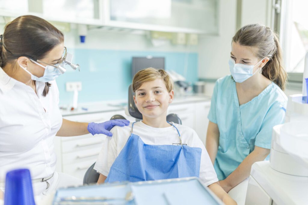 Zahnärztin Dr. Stegherr und eine Assistentin bei der Behandlung eines jungen Patienten.