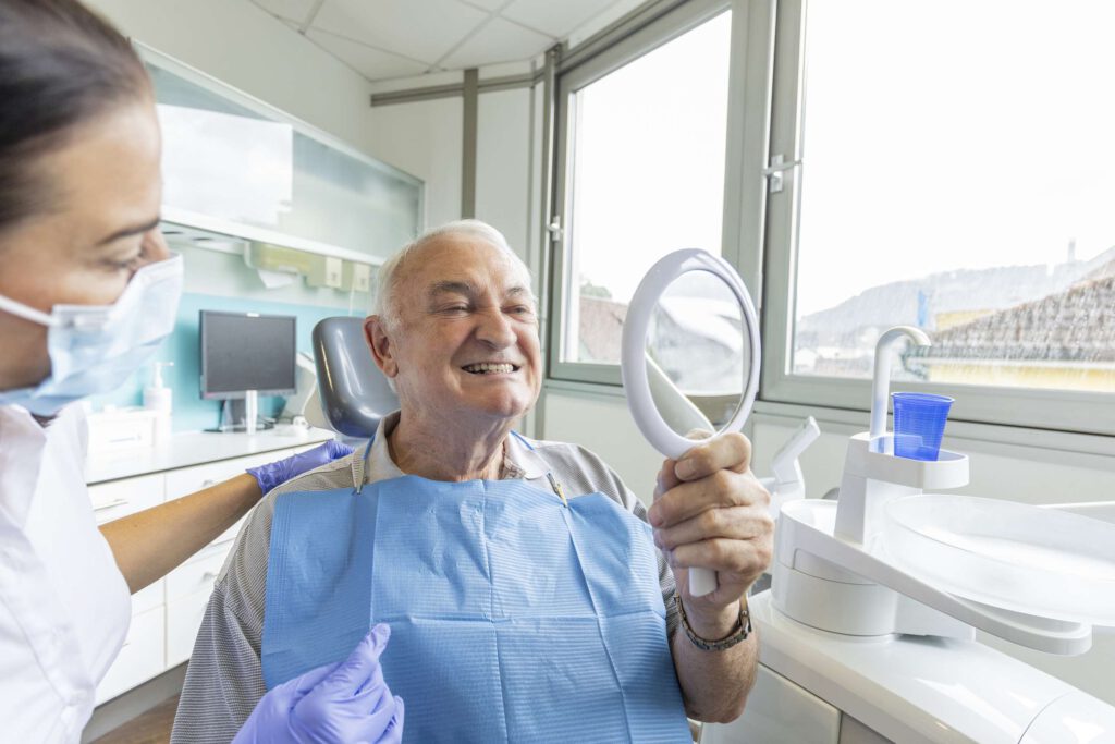 Patient begutachtet im Spiegel seine neuen Implantate.